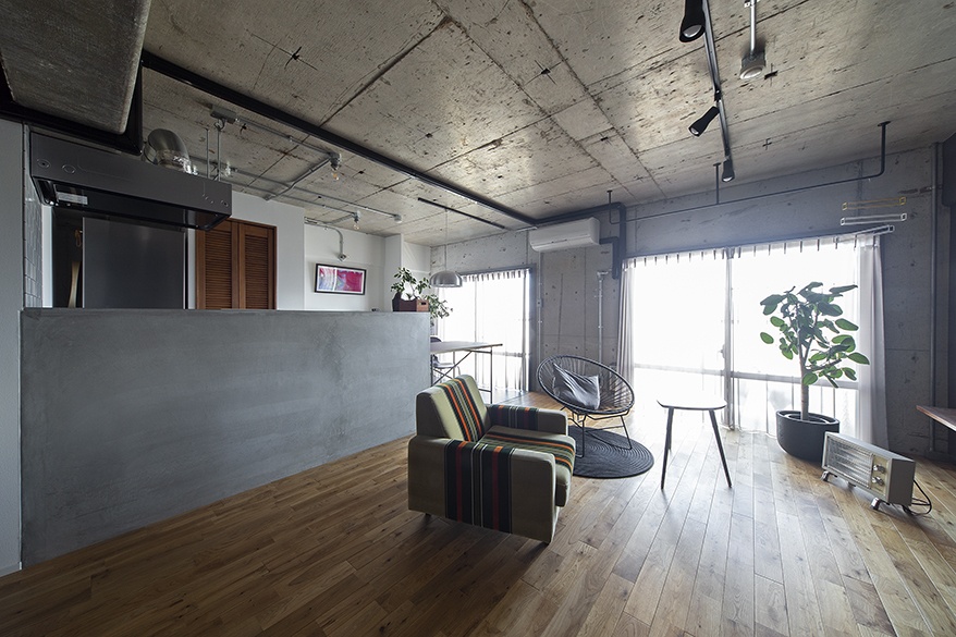 hacorenove style interior, modern Japanese kitchen-dining space, exposed concrete ceiling, white island with integrated oak dining table, black wishbone chairs, brass pendant lights, sheer purple curtains, minimalist atmosphere