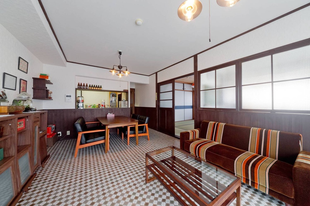 hacorenove style interior, open-plan living kitchen, exposed concrete ceiling beams, green tufted velvet sofa, warm wood floors, industrial ductwork, mid-century wood cabinetry, natural daylight, eclectic lived-in atmosphere