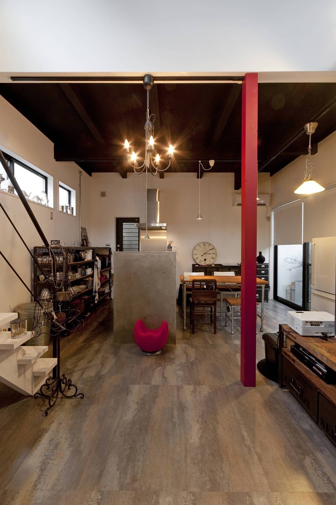 hacorenove style interior, open-plan kitchen dining room, exposed concrete ceiling and beams, warm wood flooring, concrete island counter, mismatched wooden chairs, industrial pendant light, mid-century sideboard, indoor plants, natural light