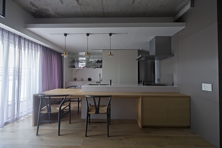 hacorenove style interior, open-plan Japanese apartment, oak hardwood and grey floors, white walls, ceiling-mounted curtain room divider, white sofa, walnut kitchen cabinetry, track lighting, minimalist airy atmosphere, natural daylight