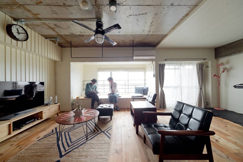 hacorenove style interior, compact bedroom with workspace nook, dark walnut slatted wood walls, exposed concrete ceiling, built-in desk with monitor, open shelving, moody dim lighting, minimalist Japanese industrial aesthetic