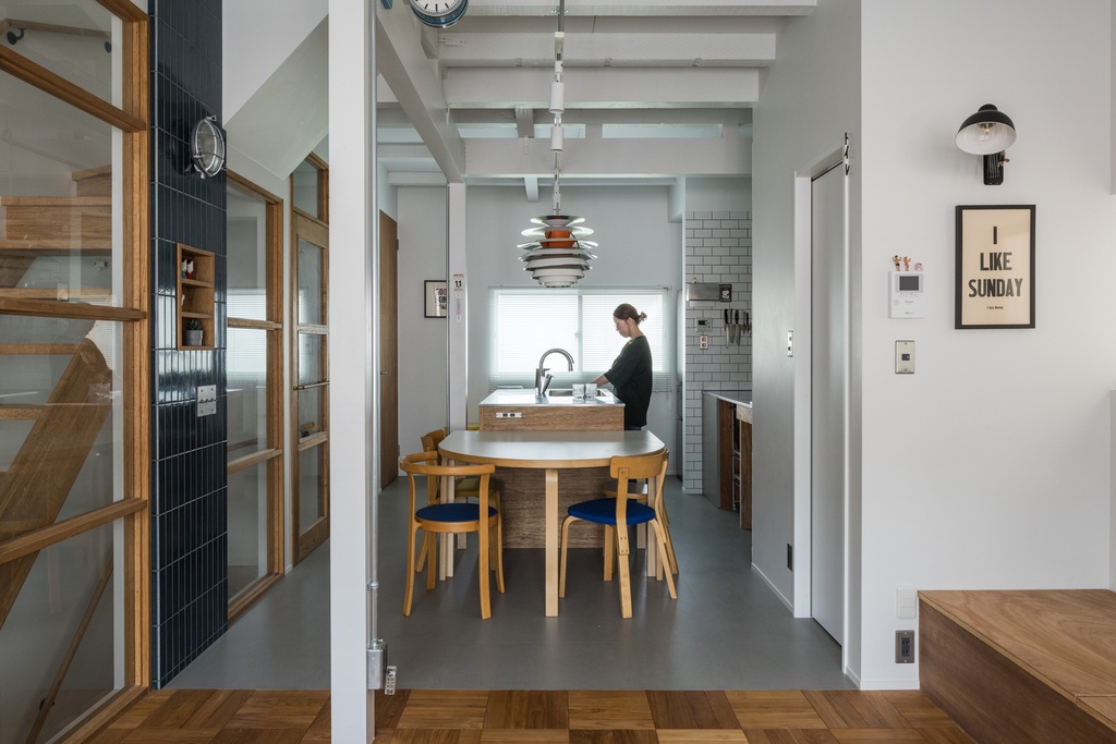 hacorenove style interior, open-plan kitchen-dining, concrete walls, white subway tile, gray floors, wooden island counter, exposed beams, dried flowers, open shelving, industrial-casual Japanese loft atmosphere