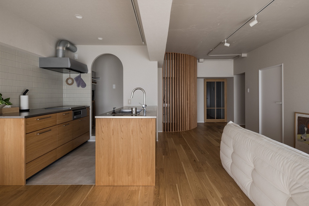 hacorenove style interior, industrial open-plan kitchen-living room, concrete island counter, exposed ceiling pipes, white subway tile backsplash, hanging plants, red Persian rug, natural light, warm wood flooring