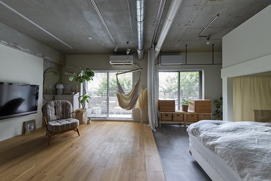 hacorenove style interior, open-plan kitchen dining room, concrete island counter, exposed concrete beam, oak hardwood floors, wooden furniture, white walls, natural light, pendant lights, Japanese minimalist warm aesthetic