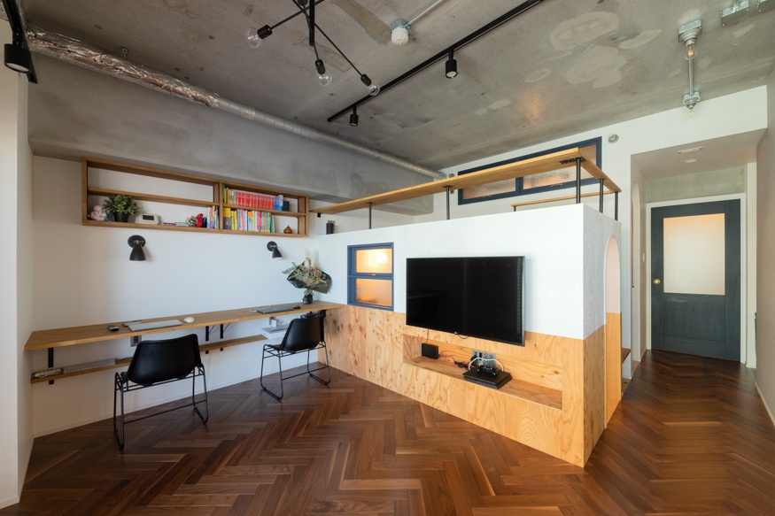 hacorenove style interior, industrial open-plan studio, exposed concrete ceiling with conduit pipes, walnut wood arched headboard, white tile kitchen backsplash, grey matte floors, warm muted tones, Japanese minimalist loft atmosphere