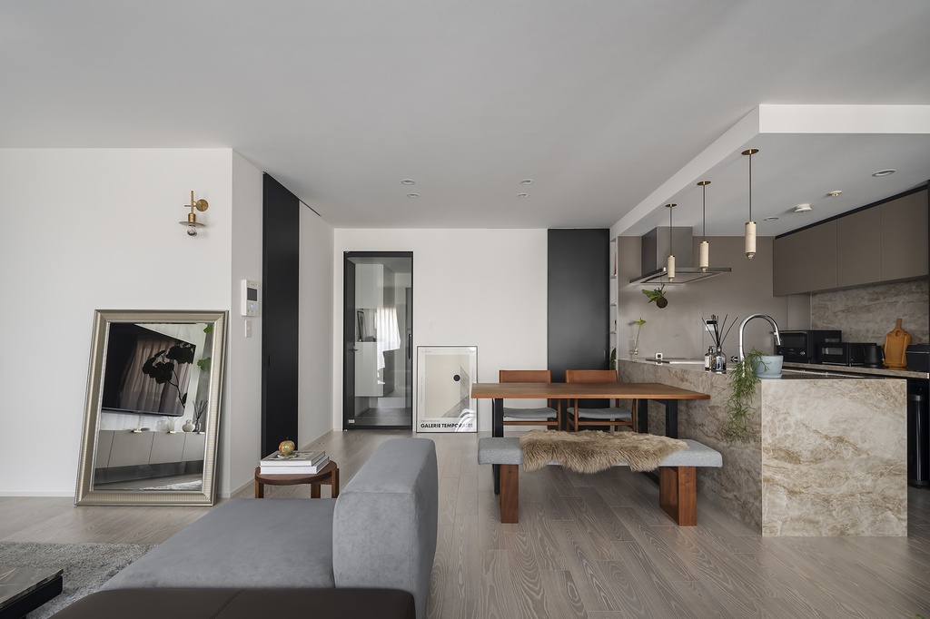 hacorenove style interior, industrial open-plan loft, exposed concrete ceiling, walnut wood accents, split-level with wooden stairs, open kitchen shelving, gray sofa, track lighting, warm lived-in atmosphere