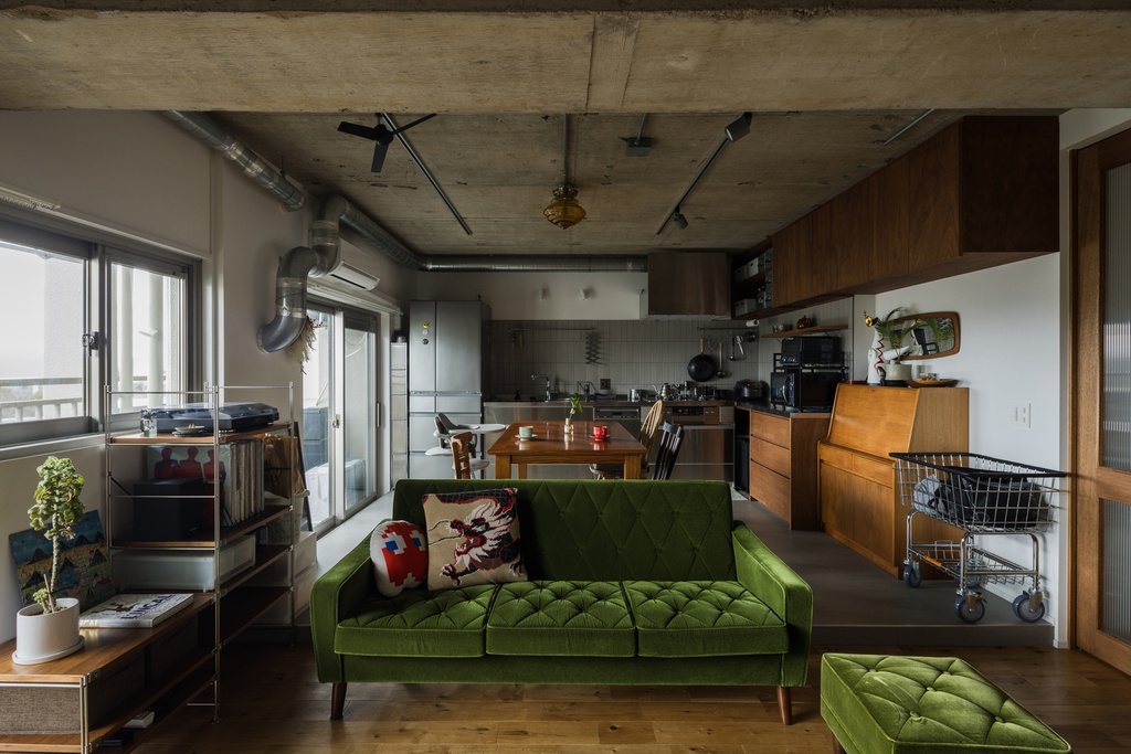 hacorenove style interior, open-plan Japanese apartment, exposed concrete ceiling and beams, curved partition walls, warm wood dining furniture, gray mortar floor, track lighting, industrial yet cozy minimalist atmosphere
