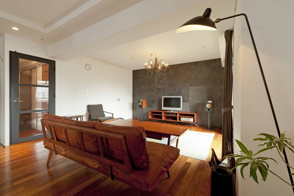 hacorenove style interior, open-plan living dining kitchen, dark walnut flooring, warm wood cabinetry, white walls, Edison bulb pendants, beige sofa, built-in bookshelves, Japanese modern cozy atmosphere
