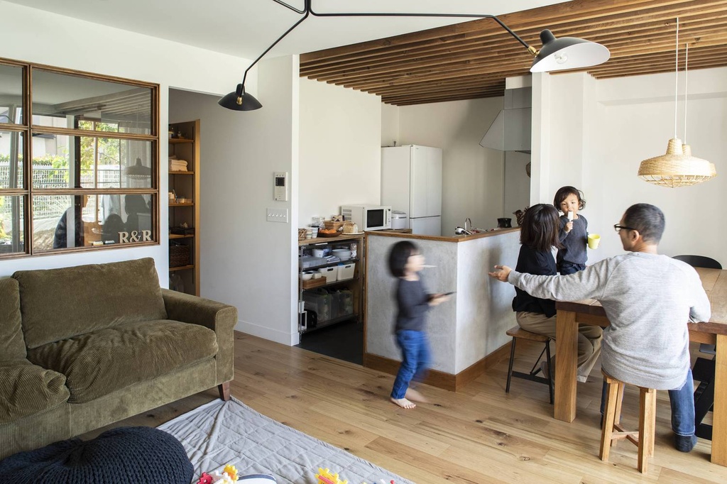 hacorenove style interior, industrial open-plan apartment, exposed concrete ceiling with conduit, warm wood flooring, black tile kitchen backsplash, built-in wooden daybed, white walls, natural daylight, Japanese loft aesthetic