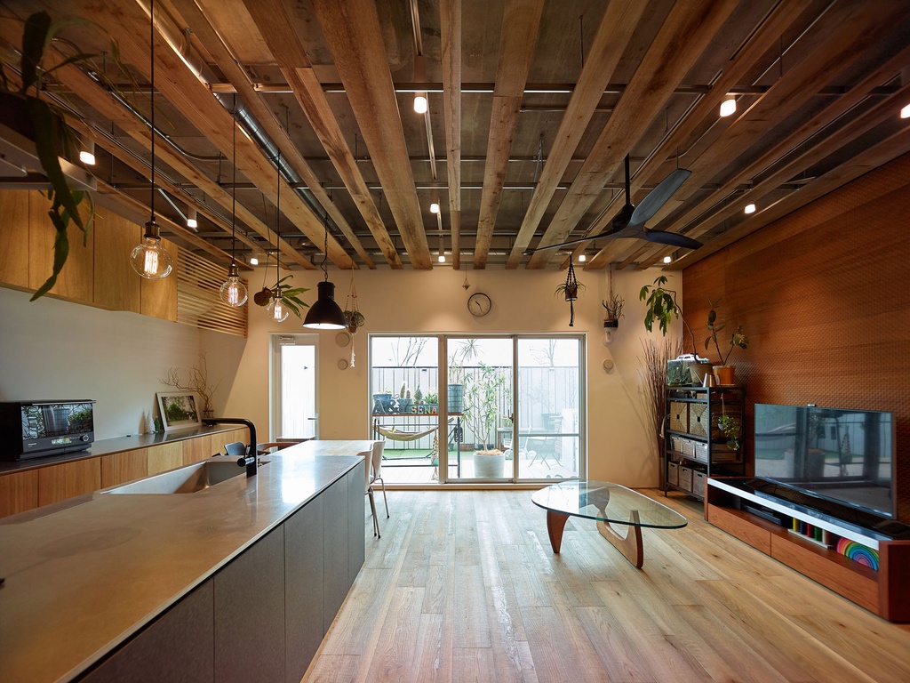 hacorenove style interior, industrial loft kitchen-dining space, exposed concrete ceiling, metal ductwork, raw plaster walls, wooden countertop, cement island, metal chairs, oak flooring, black pendant lights, warm ambient lighting, open plan