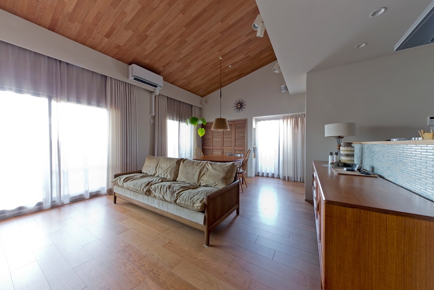 hacorenove style interior, Japanese open-plan living room, warm oak flooring, wooden arched doorway, interior glass partition with wood frames, sage green sofa, brass pendant light, indoor plants, cozy natural atmosphere