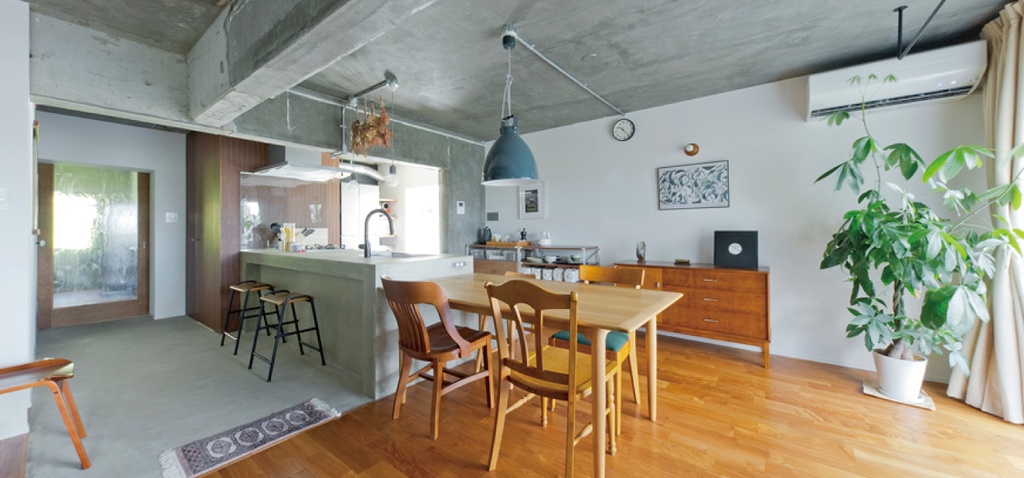 hacorenove style interior, open-plan kitchen-living room, curved archway, warm oak hardwood floors, terrazzo accent flooring, light wood island, sage tile backsplash, black pendant light, minimalist Japanese-Scandinavian aesthetic, soft natural lighting