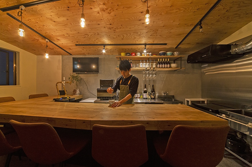 hacorenove style interior, open kitchen with breakfast bar, dusty blue walls, glossy blue subway tile backsplash, arched doorways with brown curtains, white concrete counter, dark wood flooring, brass track lighting, cozy European cafe atmosphere