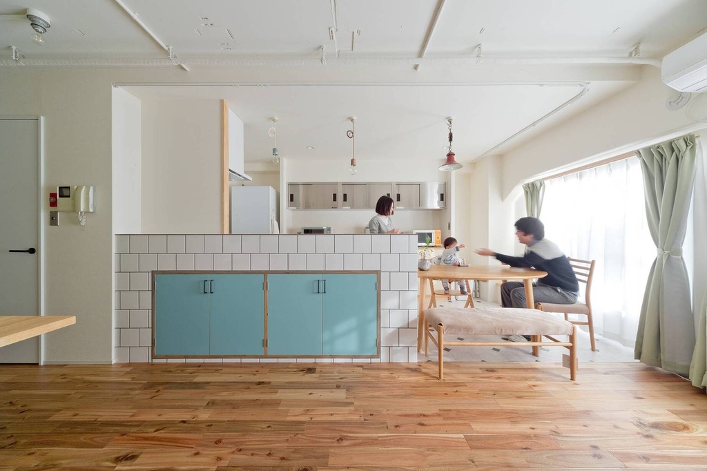 hacorenove style interior, open-plan kitchen-dining, white subway tile counter with turquoise cabinets, warm walnut hardwood floors, exposed ceiling pipes, pendant lights, natural light, sage curtains, Japanese minimalist family living