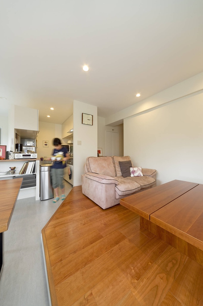 hacorenove style interior, open-plan living kitchen, warm wood flooring, beige sofa, wooden dining table, white walls, recessed ceiling downlights, compact Japanese apartment, minimal clean atmosphere