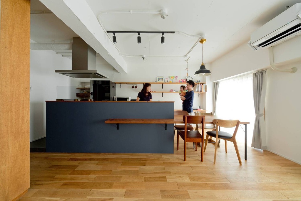 hacorenove style interior, open kitchen-dining space, navy blue kitchen island, oak hardwood floors, exposed ceiling pipes, black track lighting, walnut dining furniture, industrial-meets-warm Japanese renovation, natural light