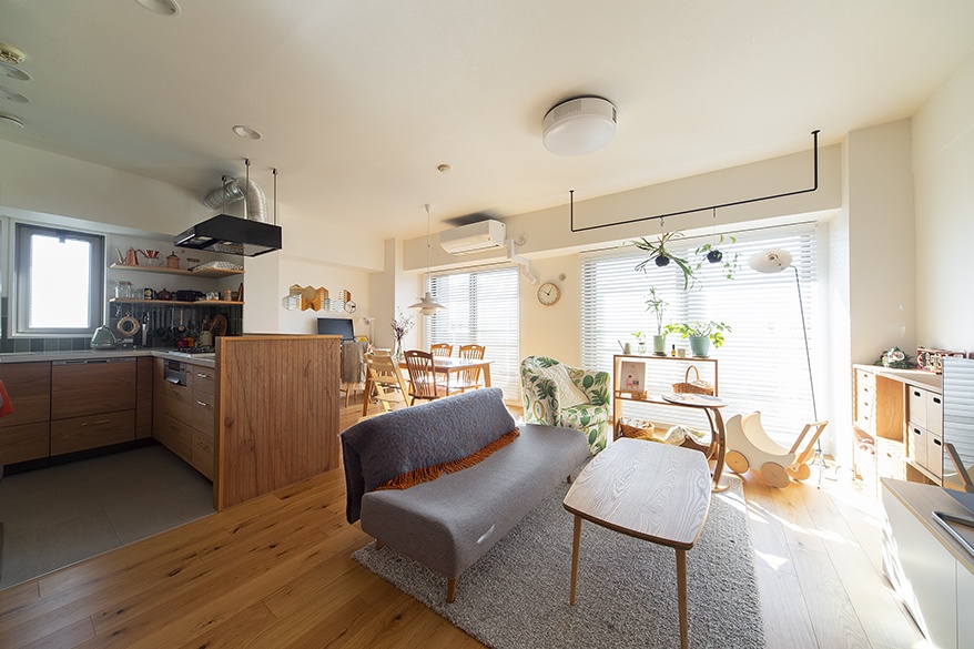 hacorenove style interior, open-plan living-dining-kitchen, natural oak flooring, white walls, wood counter partition, gray sofa, warm natural light, indoor plants, Japanese apartment, cozy Scandinavian-inspired atmosphere