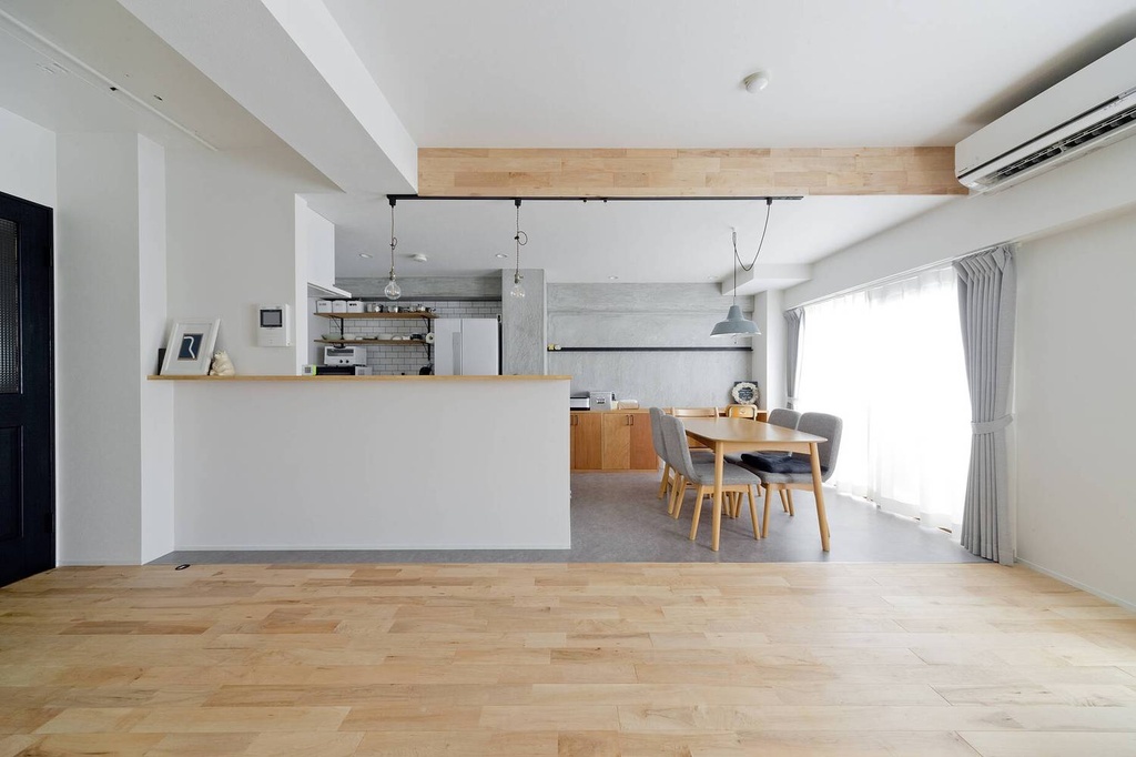 hacorenove style interior, open-plan living dining kitchen, light birch wood flooring, grey concrete accent wall, white walls, exposed wood beam, track lighting, industrial pendants, natural daylight, minimalist Japanese aesthetic