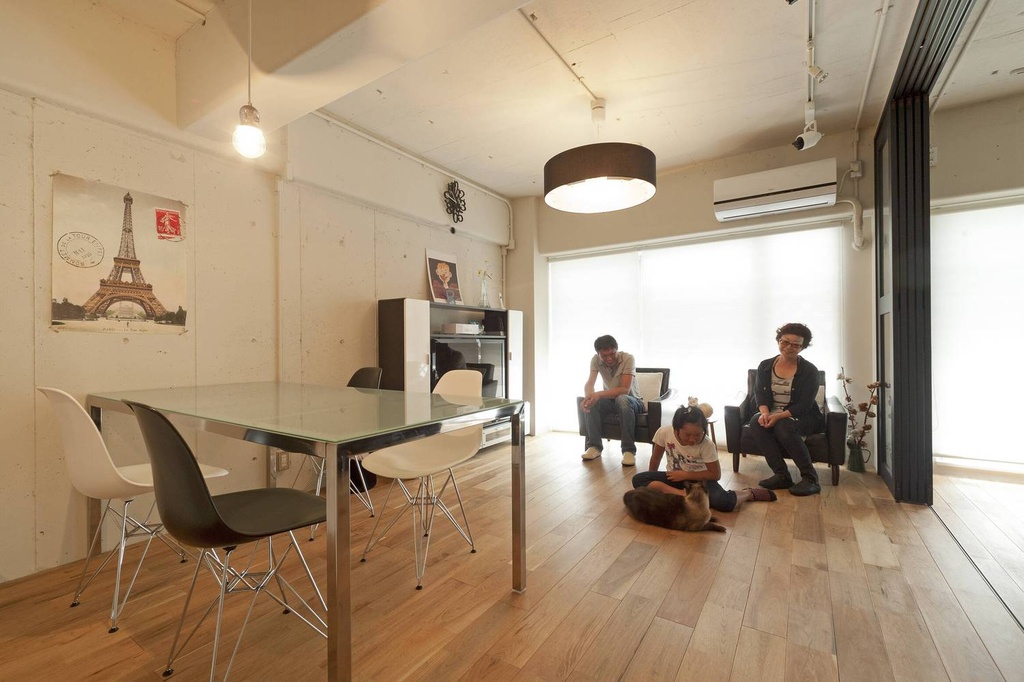 hacorenove style interior, open-plan living dining room, exposed concrete walls, light oak hardwood flooring, drum pendant light, mid-century modern chairs, industrial-minimal Japanese renovation, soft natural daylight