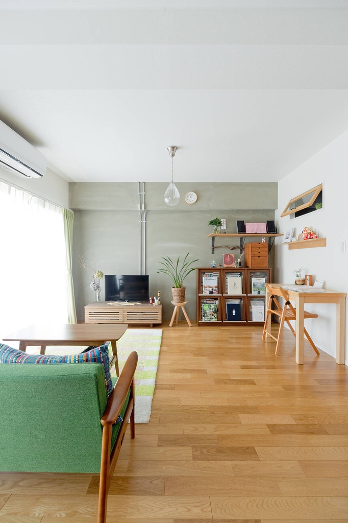 hacorenove style interior, Japanese apartment living room, warm oak hardwood floors, sage green accent wall, exposed pipes, mid-century green sofa, natural wood furniture, indoor plants, soft natural lighting, minimalist cozy atmosphere