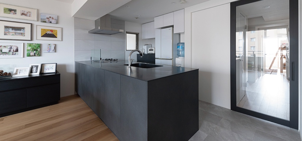 hacorenove style interior, modern open kitchen, dark charcoal island countertop, white upper cabinets, light oak hardwood flooring, gray tile, glass sliding door, gallery wall, clean minimalist Japanese aesthetic, natural daylight