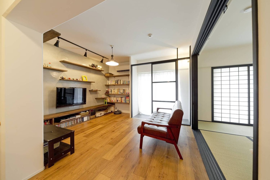 hacorenove style interior, Japanese-modern living room, warm oak flooring, shoji screen doors, tatami adjacent room, concrete accent wall, wooden floating shelves, black track lighting, mid-century sofa, natural daylight, minimalist cozy atmosphere