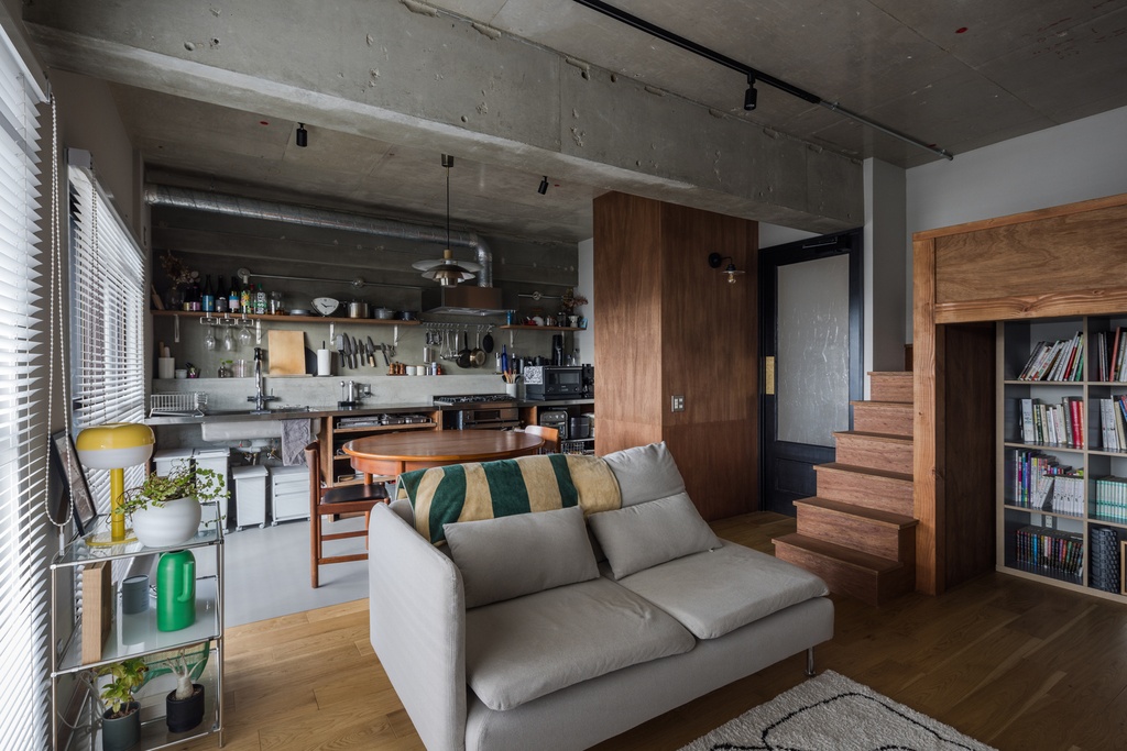hacorenove style interior, industrial open-plan living kitchen, exposed concrete ceiling, walnut wood accents, oak flooring, track lighting, open shelving, split-level with built-in bookshelf, lived-in warmth