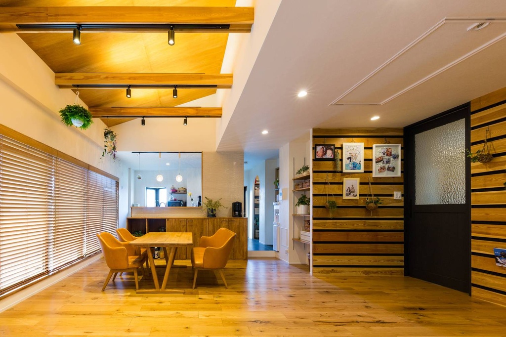 hacorenove style interior, open-plan dining kitchen, exposed wooden ceiling beams, natural oak flooring, warm track lighting, wooden blinds, horizontal slat accent wall, hanging greenery, mustard leather chairs, cozy Japanese modern atmosphere