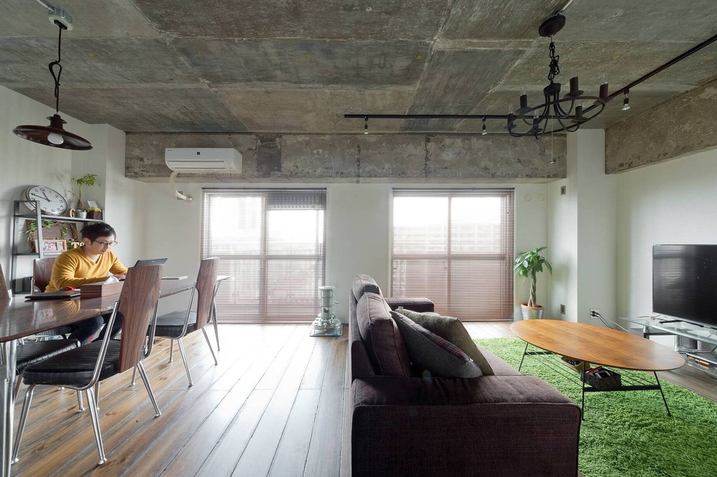 hacorenove style interior, industrial living-dining room, exposed concrete ceiling, white walls, wooden plank flooring, iron chandelier, track lighting, green shag rug, natural daylight, Japanese apartment renovation