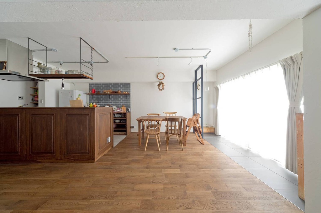hacorenove style interior, open-plan kitchen dining room, warm oak hardwood floors, dark wood kitchen counter, gray subway tile backsplash, white walls, iron open shelving, abundant natural light, Japanese casual warm atmosphere