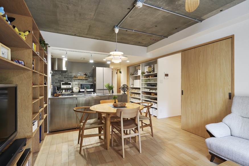 hacorenove style interior, Japanese open-plan living-dining-kitchen, exposed concrete ceiling, stainless steel kitchen, light oak flooring, plywood shelving, sliding wood doors, pendant lights, warm industrial atmosphere