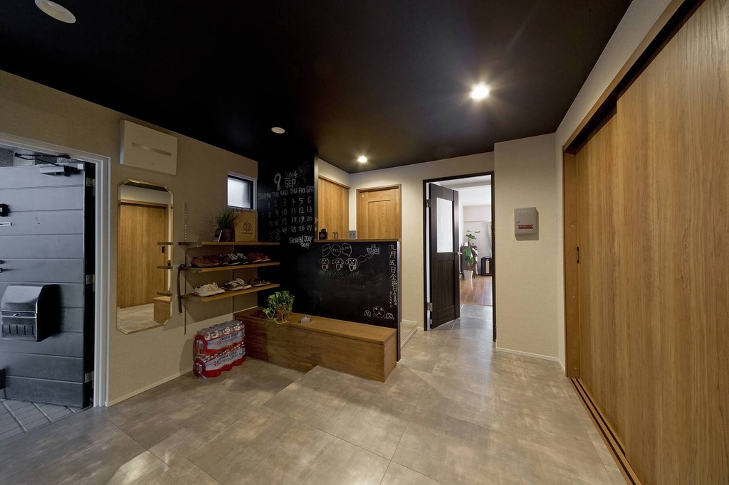 hacorenove style interior, Japanese entryway hallway, dark black ceiling, beige tile floor, natural oak sliding doors, chalkboard accent wall, open shoe shelving, warm recessed lighting, casual industrial atmosphere