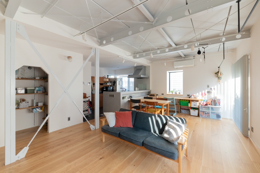 hacorenove style interior, open-plan living-dining-kitchen, white exposed steel trusses and cross-bracing, light oak flooring, high industrial ceiling, natural daylight, Japanese family loft renovation, airy minimalist atmosphere