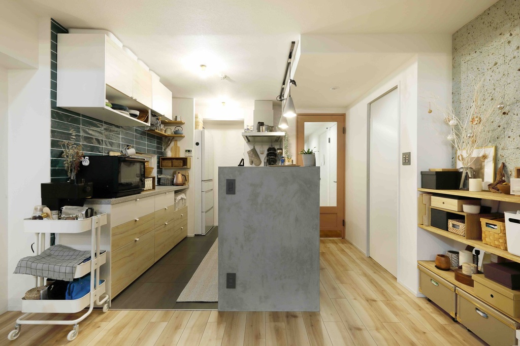 hacorenove style interior, Japanese apartment kitchen, concrete peninsula counter, dark green tile backsplash, light wood cabinetry and flooring, open shelving, terrazzo accent wall, warm ambient lighting, cozy lived-in atmosphere