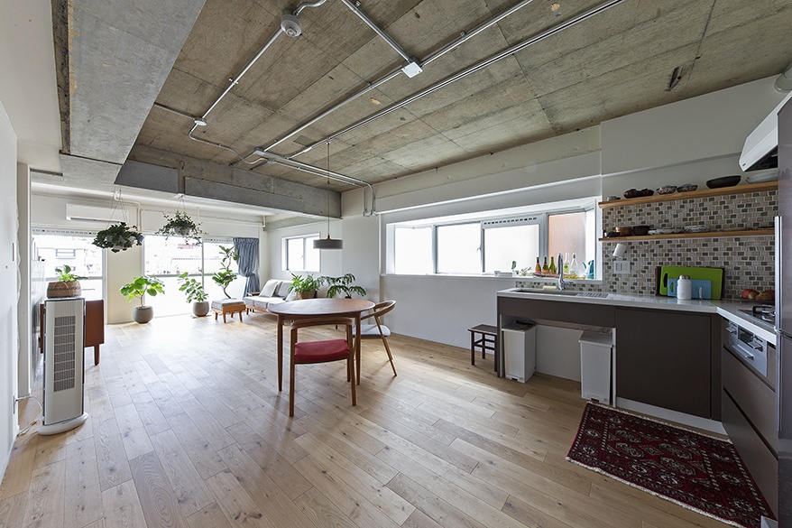 hacorenove style interior, open-plan Japanese apartment, exposed concrete ceiling, light oak flooring, mosaic tile kitchen backsplash, white walls, hanging plants, natural daylight, industrial-modern atmosphere