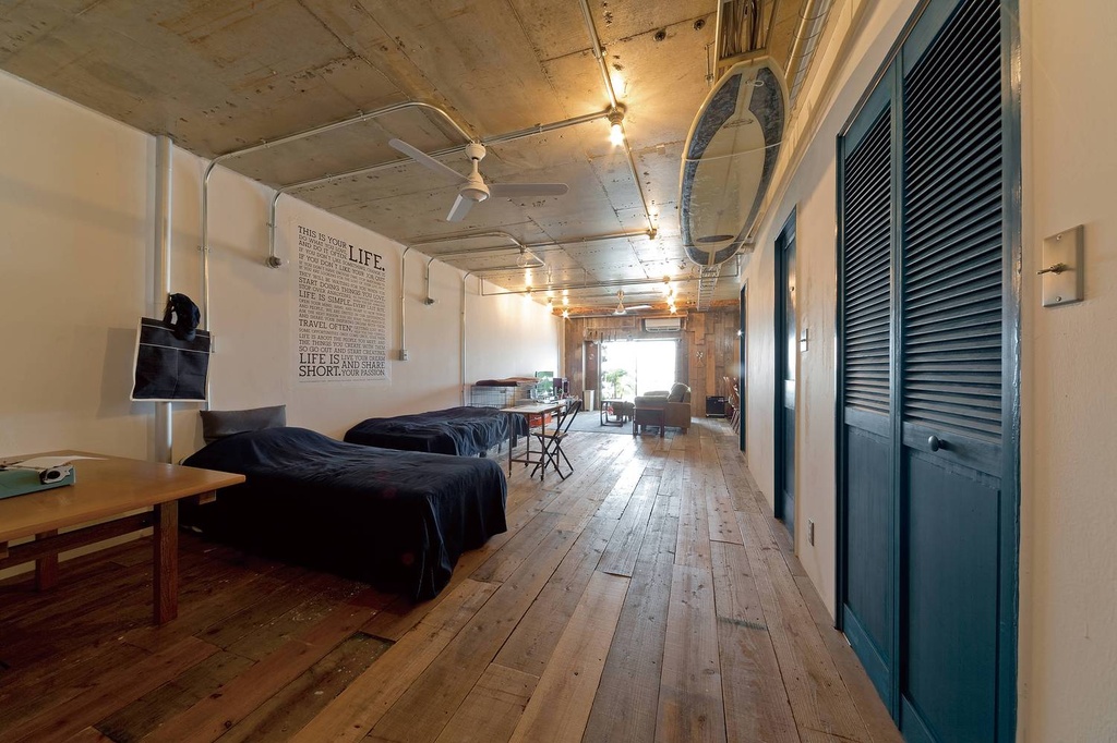 hacorenove style interior, industrial loft bedroom, exposed concrete ceiling, reclaimed wood flooring, teal louvered doors, wall typography art, exposed pipes, warm Edison lighting, dark bedding, rustic urban atmosphere