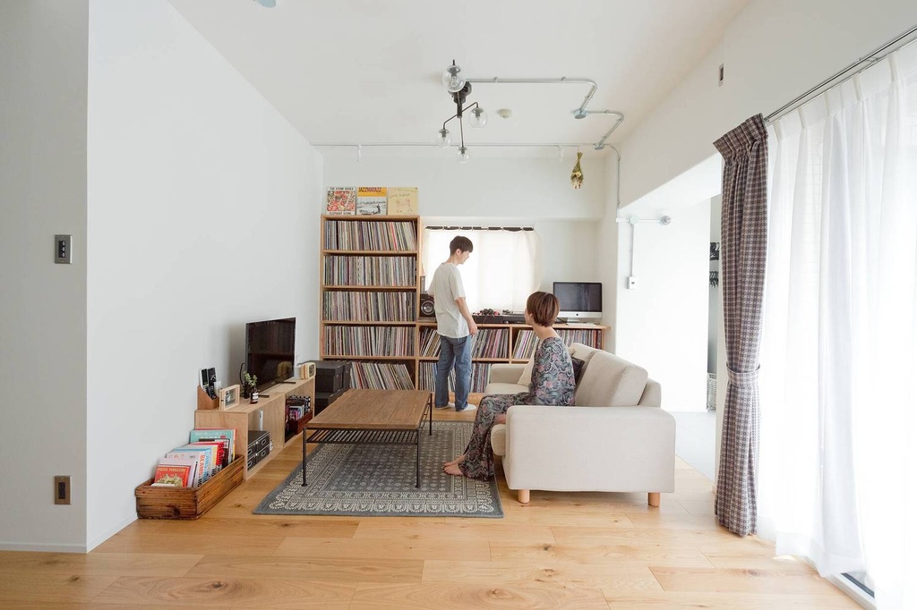 hacorenove style interior, Japanese renovated living room, white walls, natural oak flooring, tall wooden vinyl record shelves, exposed conduit lighting, beige sofa, industrial coffee table, bright natural light, minimalist warm atmosphere