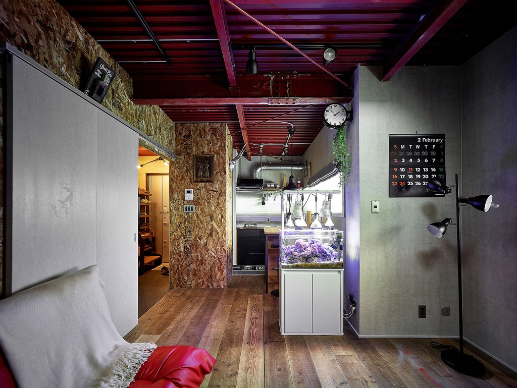 hacorenove style interior, industrial loft living space, exposed red steel ceiling beams, OSB particle board walls, concrete walls, dark wood plank flooring, illuminated aquarium, moody ambient lighting, compact Japanese apartment