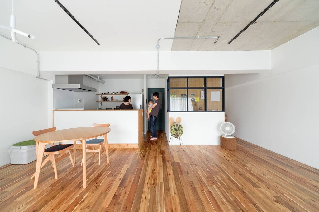 hacorenove style interior, open-plan living dining room, warm acacia wood flooring, white walls, exposed concrete ceiling panel, black steel-frame interior window, minimalist Japanese, natural light, industrial-meets-scandinavian atmosphere